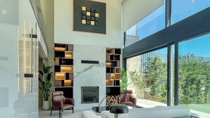 A modern living room with a fireplace, a glass coffee table, and a large window offering a view of the outdoors. - Beykoz Breeze (Beykoz)