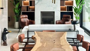 A modern living room with a marble fireplace, built-in shelving, leather chairs, and a unique wooden coffee table. - Beykoz Breeze (Beykoz)