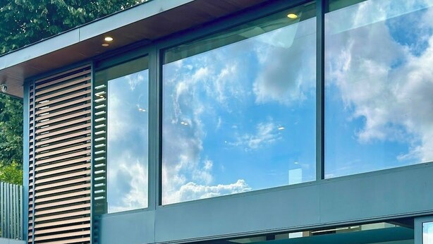 A modern house with a glass facade, a wooden slatted wall, a staircase, and a dining area with chairs and a table. - Beykoz Breeze (Beykoz)