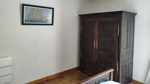 Una habitación con un armario de madera, un cuadro en la pared y una lámpara colgante.