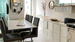 A modern kitchen with a dining table, chairs, and a refrigerator. - 4 Star Holiday Home in Laholm (Skummesloevsstrand)