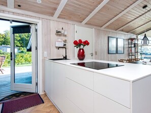 A modern kitchen with a large island, white cabinetry, and a red vase with flowers.