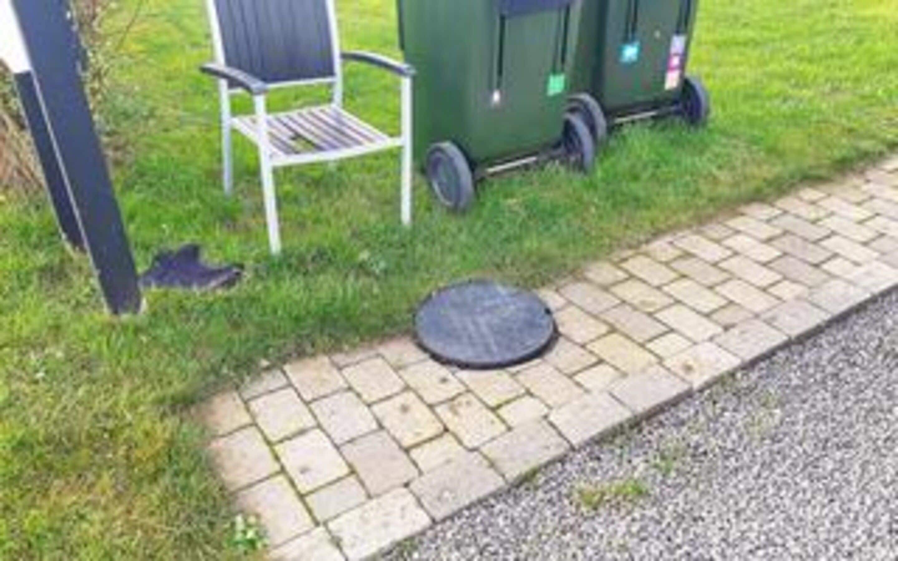 A paved pathway, a metal chair, and a green utility cart.