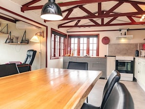 A kitchen with a wooden table, chairs, a clock, and a stove. - 6 Person Holiday Home in Logstor (Logstor)
