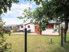 A residential area with a white house with red trim, a patio with chairs, and a fenced yard. - 6 Person Holiday Home in Logstor (Logstor)