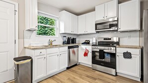 A modern kitchen with white cabinets, stainless steel appliances, and a granite countertop.