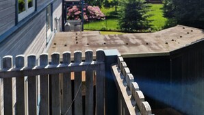 A wooden deck with a view of a garden and a house. - Vacation apartment WaldZeit in Hahnenklee - with dog (Goslar)