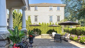 A patio area with stone flooring, outdoor furniture, and umbrellas. - Historic City View Loft - Walk to Newport's Best (Newport)