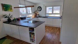 Una cocina moderna con armarios blancos, encimera negra y ventana que proporciona luz natural.