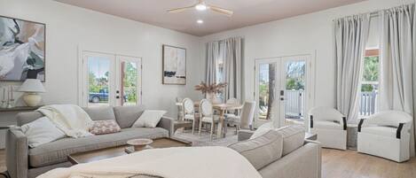 A spacious living room with a sofa, chairs, a dining table, and a ceiling fan.