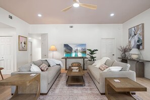 Ein Wohnzimmer mit zwei Sofas, einem Couchtisch und einem Deckenventilator.