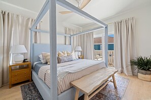 Un lit à baldaquin avec un cadre en bois, une table de chevet avec une lampe et une plante en pot.