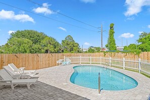 Une piscine entourée d’une clôture en bois et dotée de chaises longues.