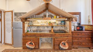 A rustic kitchen with wooden beams, a refrigerator, a microwave, and a wooden cabinet with drawers.