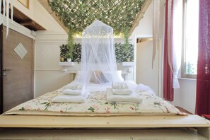 A bed with a floral bedspread, white towels, and a canopy.