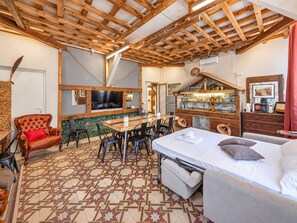 A cozy room with a wooden ceiling, a dining area with chairs, a bed with pillows, and a TV mounted on the wall. - 4BNB - Victoria Palace (Rome)