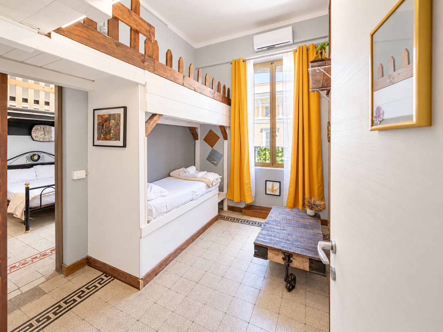 Une chambre avec des lits superposés, un bureau et une fenêtre avec des rideaux.