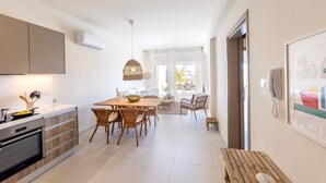 Una cocina moderna con comedor, una mesa de madera, sillas de mimbre y vistas al exterior.