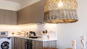 Una cocina moderna con lavadora integrada, cafetera y lámpara colgante.