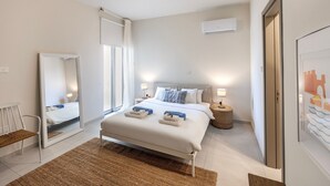 Un dormitorio moderno con una cama grande, lámparas de noche, un espejo y un cuadro en la pared.