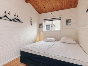 A bedroom with a bed, wooden ceiling, white walls, and a window. - 5 Person Holiday Home in Nakskov (Nakskov)