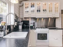 A kitchen with white cabinets, a black countertop, a stove, and a window with a view of trees.