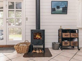 A room with a wood-burning stove, a wicker basket, a metal shelf with wooden boxes, and a door with a glass panel.