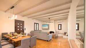 Un vaste espace de vie doté d’un parquet en bois disposé en point de Hongrie, d’un canapé gris et d’une table à manger mise avec des assiettes et des verres.