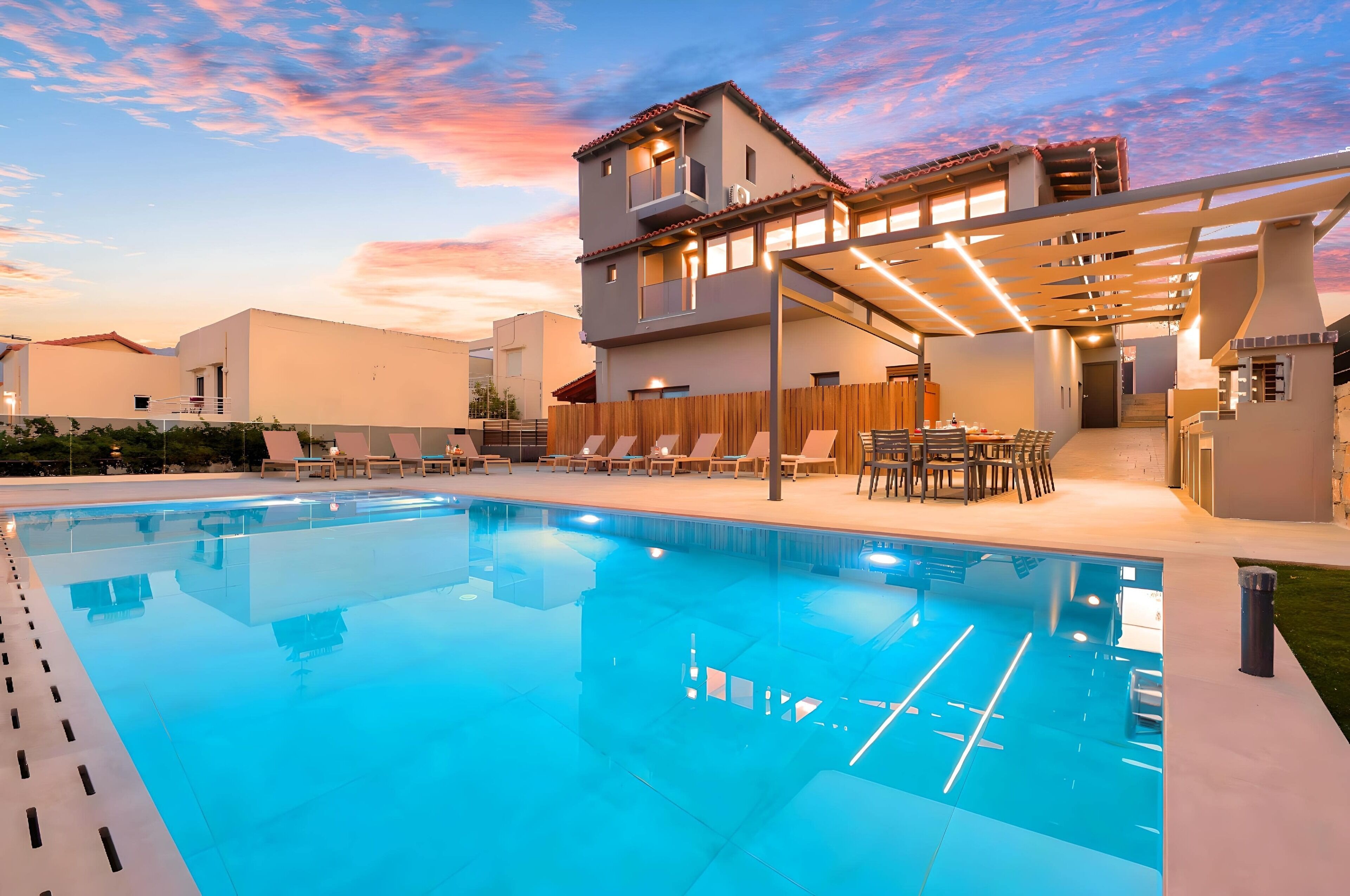 Ein moderner Poolbereich mit klarem Pool, Liegestühlen und einer überdachten Sitzgelegenheit.