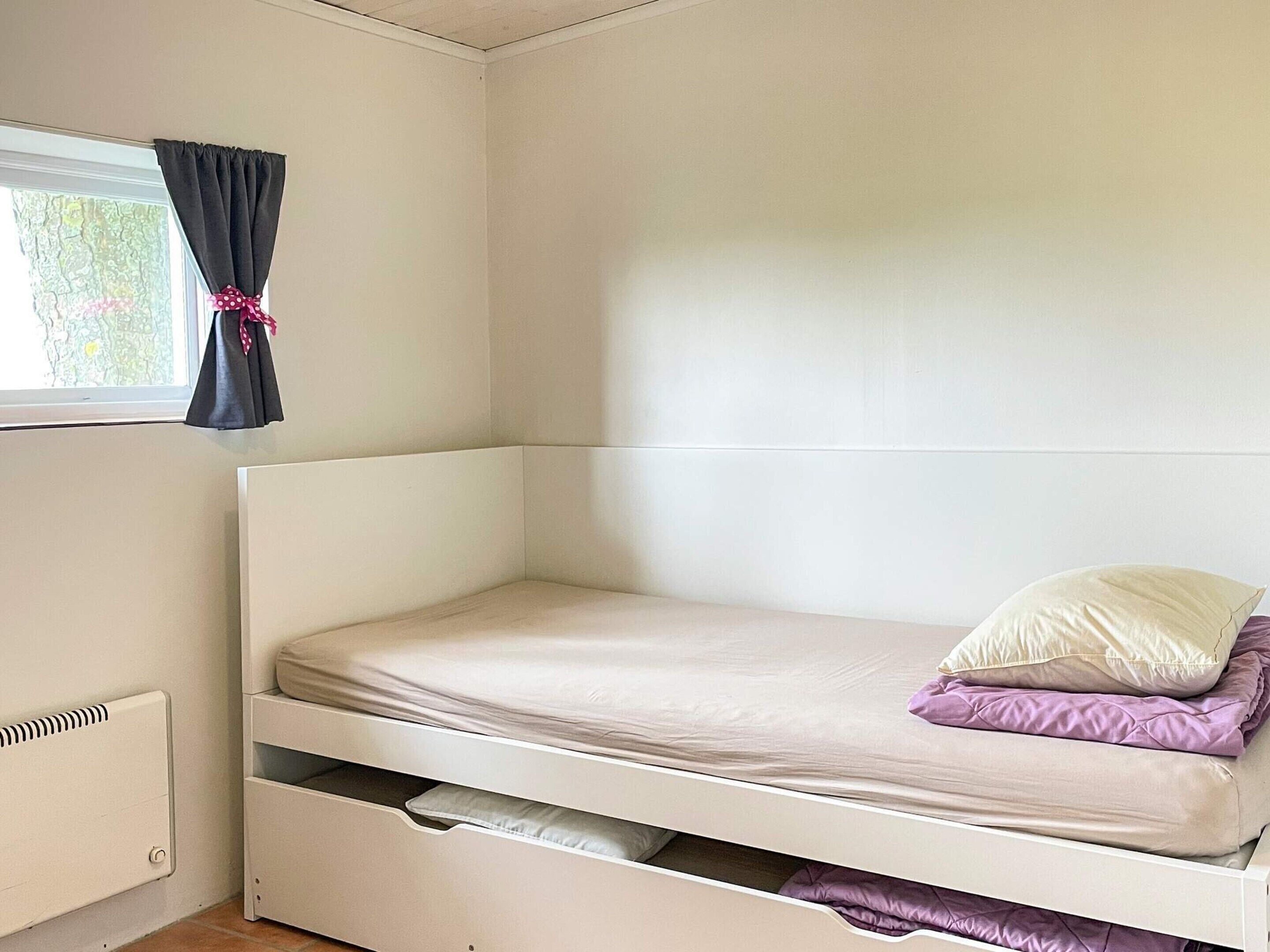 A bunk bed with a window, a radiator, and a curtain.