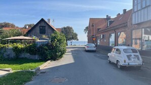 A street view with a vintage car parked on the side, a manhole cover on the road, and a building with a visible window. - 4 Person Holiday Home in Kopingebro (Köpingebro)