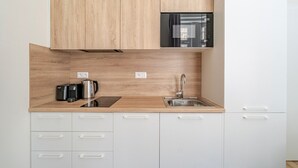 Een moderne keuken met houten kastjes, een roestvrijstalen spoelbak en een zwarte waterkoker.