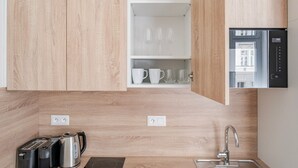 Een moderne keuken met houten kastjes, een inbouwoven, een spoelbak en een koffiezetapparaat.