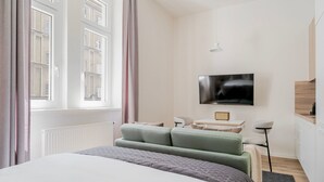 Een moderne hotelkamer met een groot bed, een flatscreen-tv, een zithoekje en uitzicht op de stad.