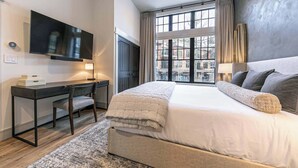 A modern bedroom with a large bed, a desk, and a TV mounted on the wall. - Catamount Lodge 101 - 2 Bedroom (Truckee)