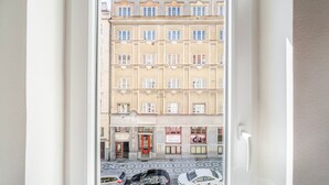 A view through a window of a multi-story building with a red door and a signboard. - Blueground | Letná, museums, foodie area (PRG-56) (Prague)