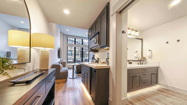 A modern kitchen with dark cabinets, a built-in oven, and a large window. - Catamount Lodge 101A -  Studio (Truckee)