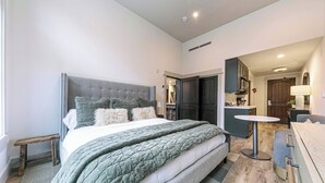 A modern bedroom with a large bed, a small table, and a sofa. - Catamount Lodge 101A -  Studio (Truckee)