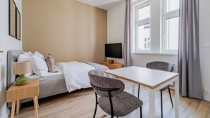 Une chambre d’hôtel moderne équipée d’un lit, d’une télévision, d’une table à manger et de deux chaises.