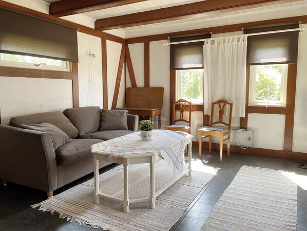 Une pièce chaleureuse avec un canapé, une petite table ornée d’une plante et deux chaises.