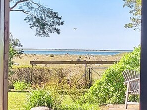 A beach view with a wooden bench, greenery, and a clear sky. - 4 Person Holiday Home in Klintehamn (Klintehamn)