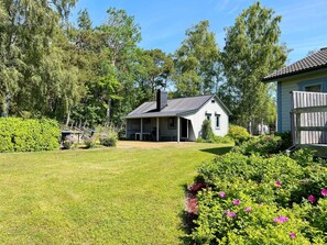A single-story house with a porch, surrounded by a well-maintained lawn and garden. - 4 Person Holiday Home in Klintehamn (Klintehamn)