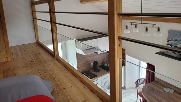 Ein modernes Schlafzimmer im Loftsstil mit Glasbalkon, Holzbalken und Blick auf die Stadt.
