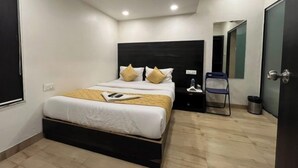 Een moderne hotelkamer met een groot bed, een nachtkastje, een stoel en een spiegel.