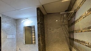 Een moderne badkamer met een marmeren wastafel, een spiegel en een douche met een glazen deur.