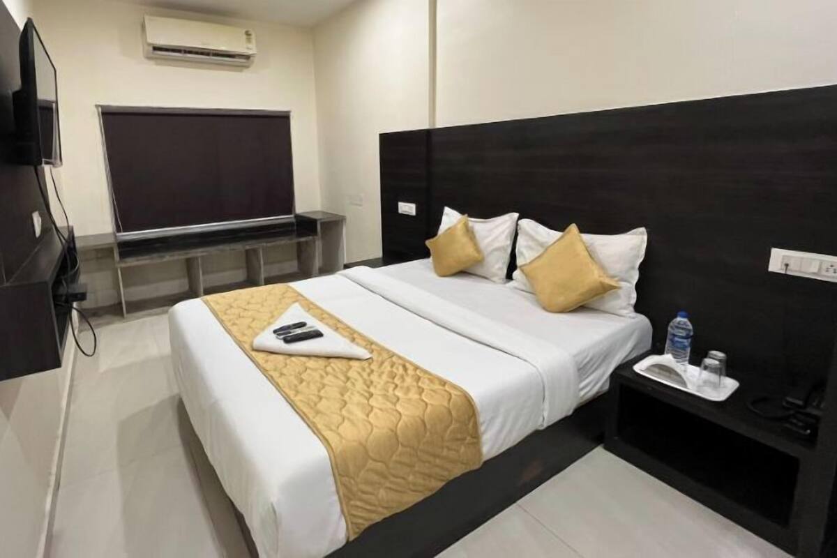 Ein Hotelzimmer mit Bett, Nachttisch, Fernseher und Schreibtisch mit Stuhl.