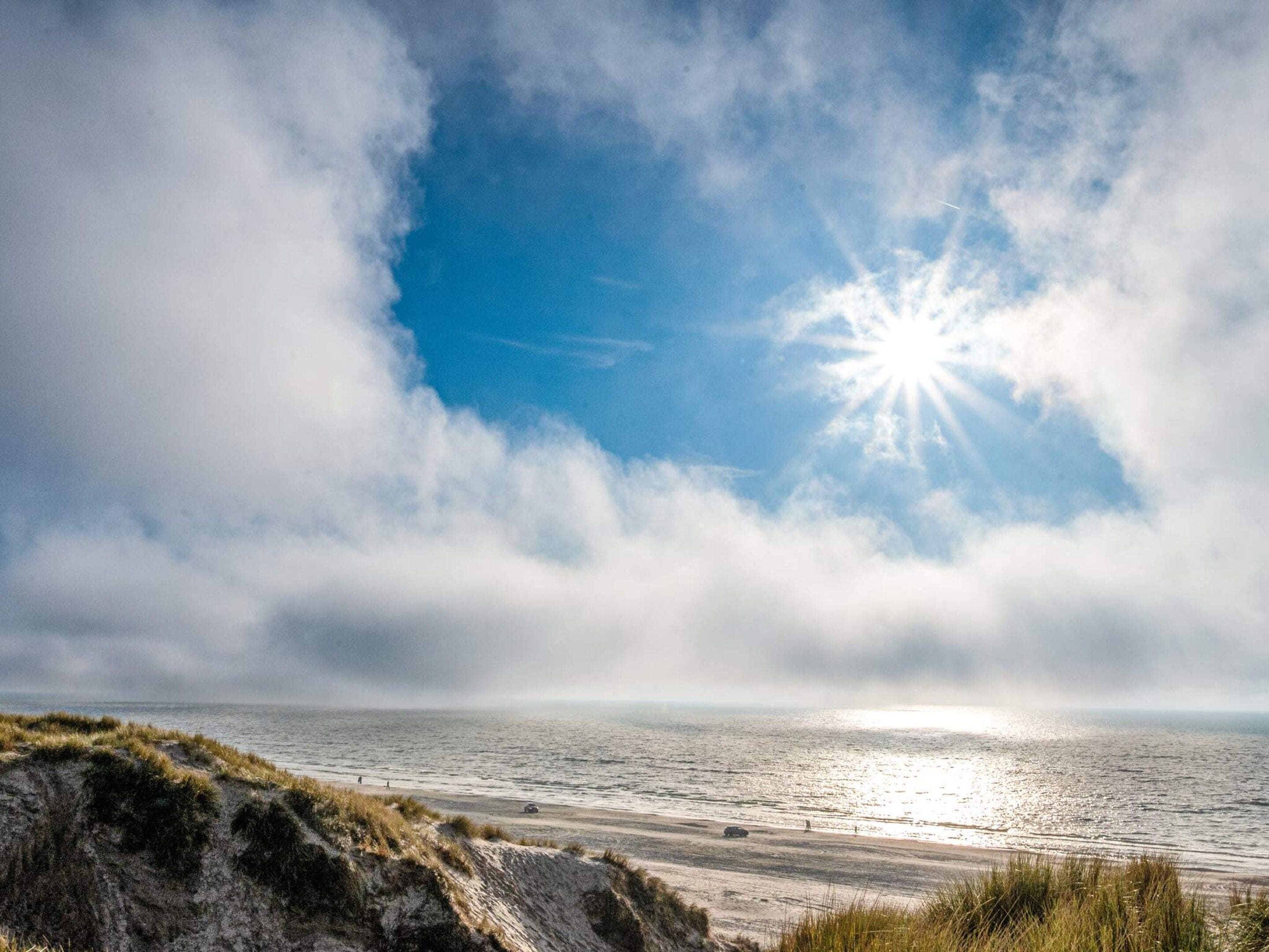 A beach with sand dunes and the ocean.