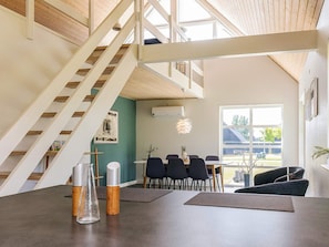 A modern interior with a staircase, dining area, and large windows. - 5 Star Holiday Home in Farso (Farso)
