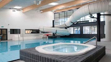Piscina interna com hidromassagem, vigas de madeira e amplas janelas.
