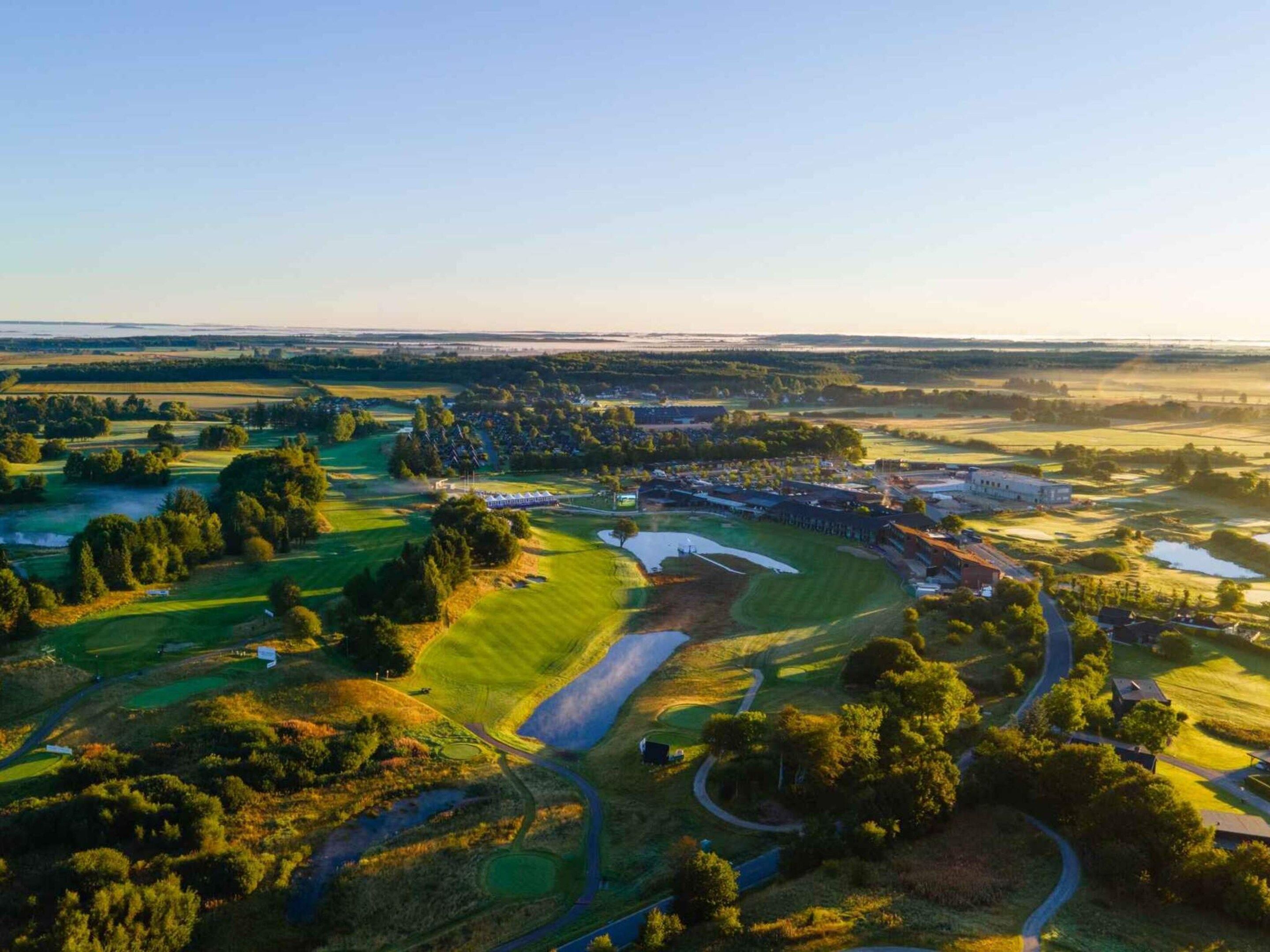 An aerial view of a golf course with multiple greens, fairways, and a clubhouse.